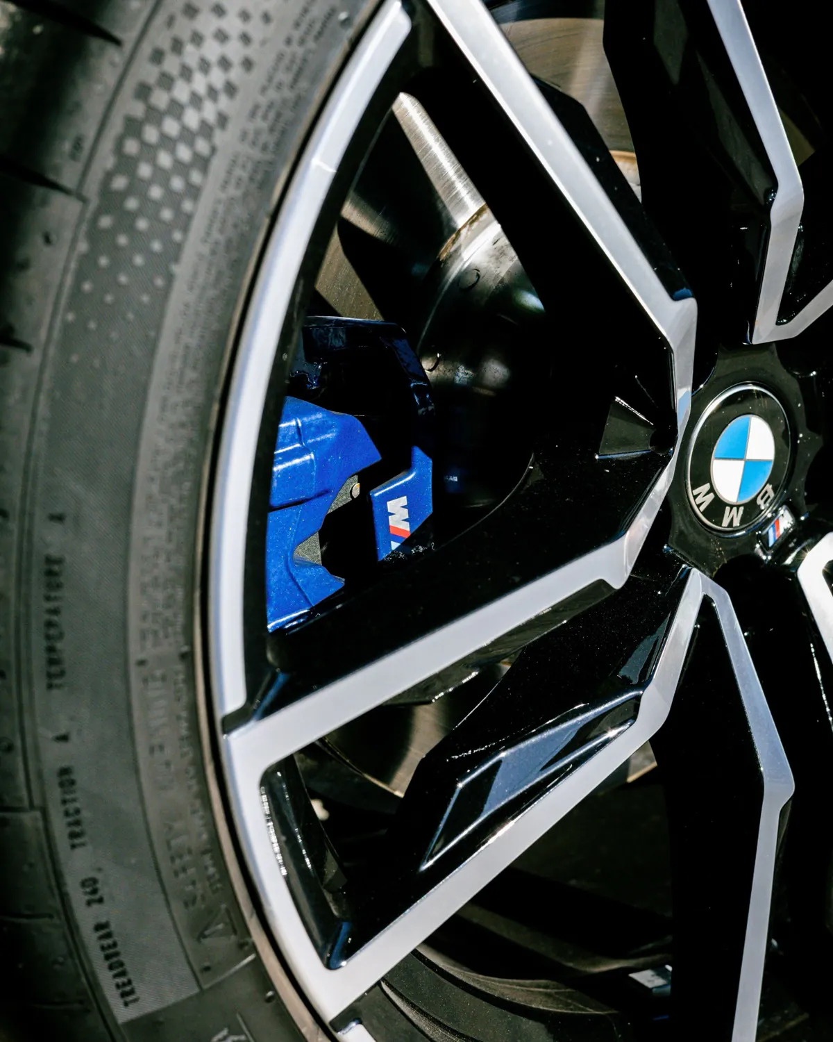 Close-up of a BMW M alloy wheel and performance tyre with blue M brake caliper